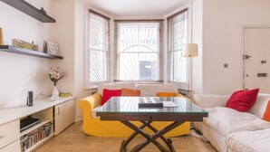 Un salon moderne avec une table à plateau en verre, un canapé et une bibliothèque.