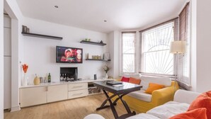 Un salon moderne avec un téléviseur à écran plat, une table à manger et un canapé.
