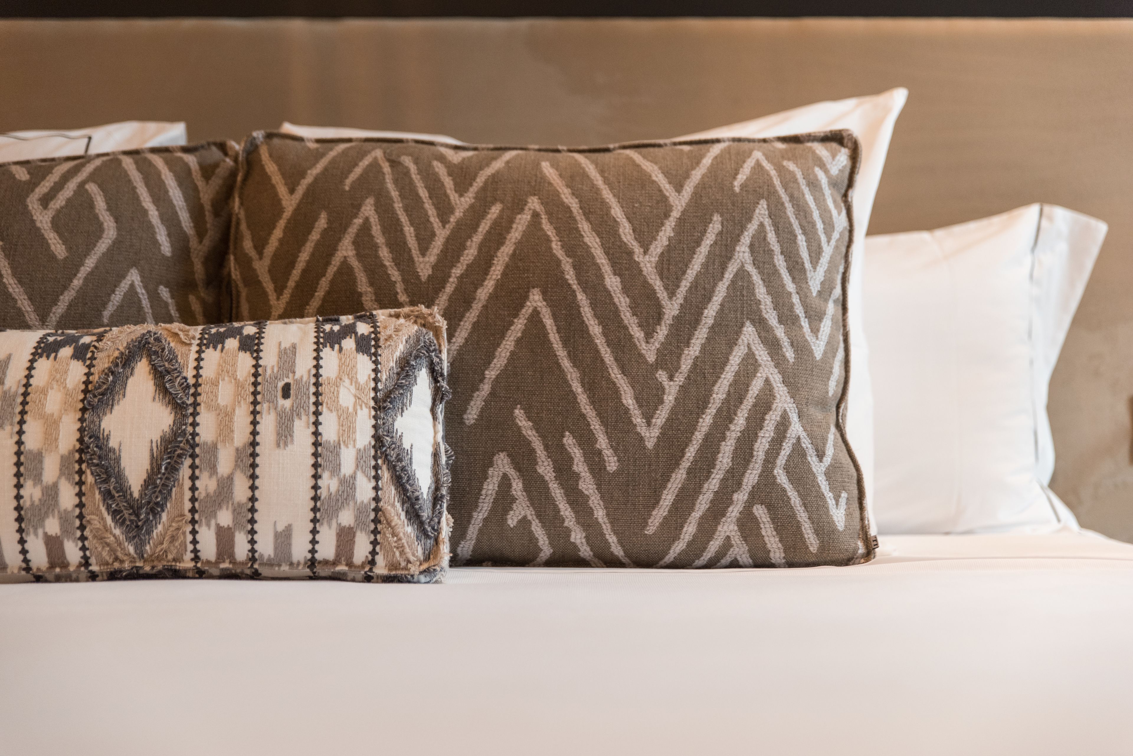 A bed with patterned pillows and a white pillow.