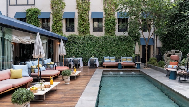 A poolside area with wooden decking, outdoor seating, and a small pool.
