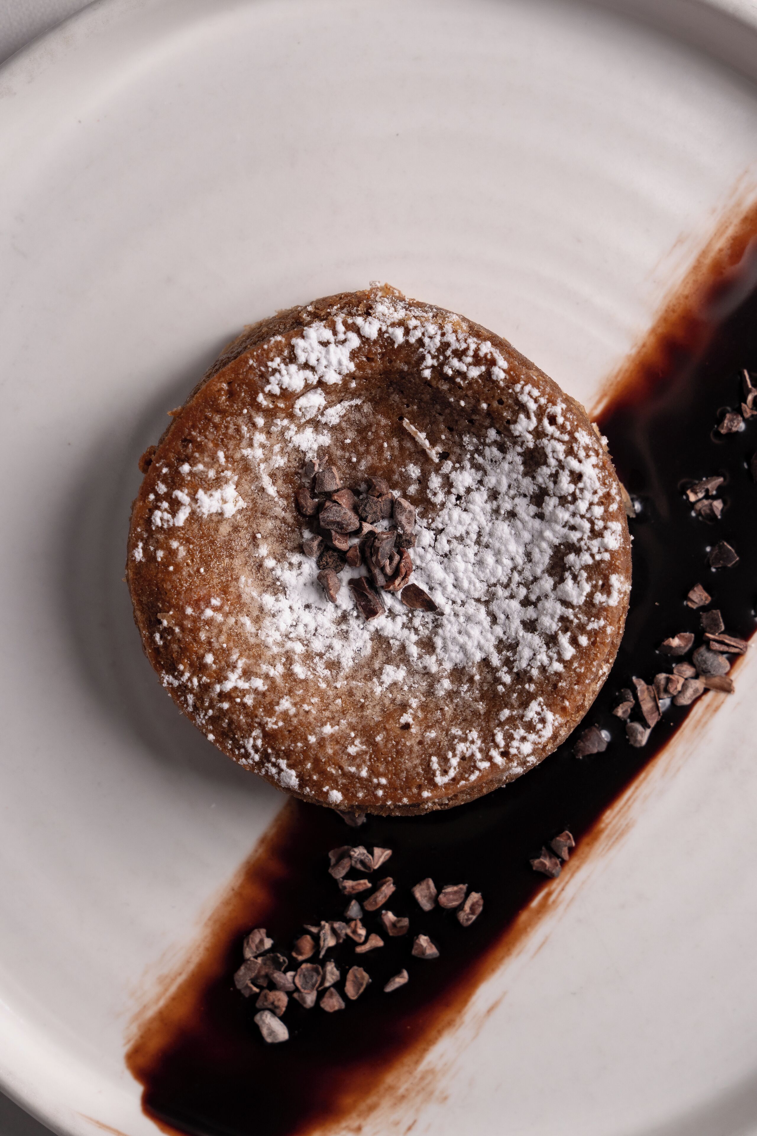 Dessert op een bord met chocoladestukjes en poedersuiker.