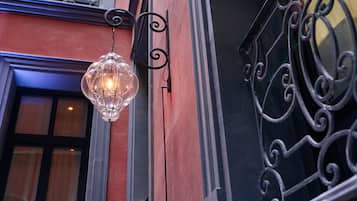 Una lámpara colgante de cristal fijada a una pared con barandilla de hierro forjado.