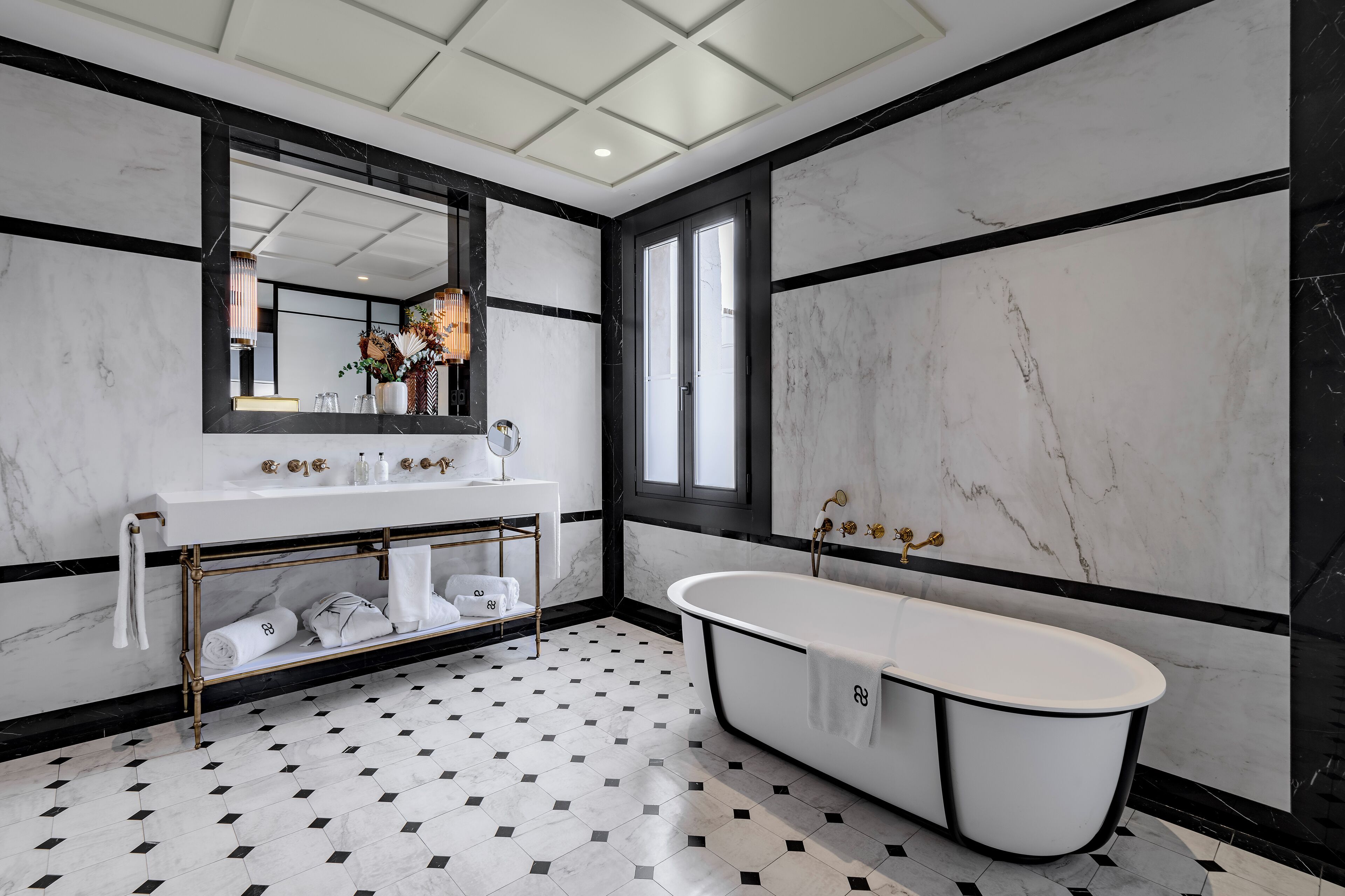 A modern bathroom with a freestanding bathtub, a vanity with a mirror, and a large window.