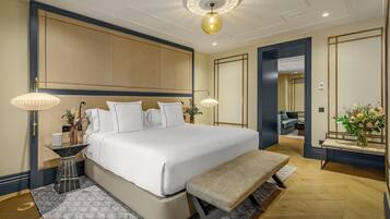 Een moderne hotelkamer met een groot bed, bedlampjes, een bankje, een tafeltje en een spiegel.