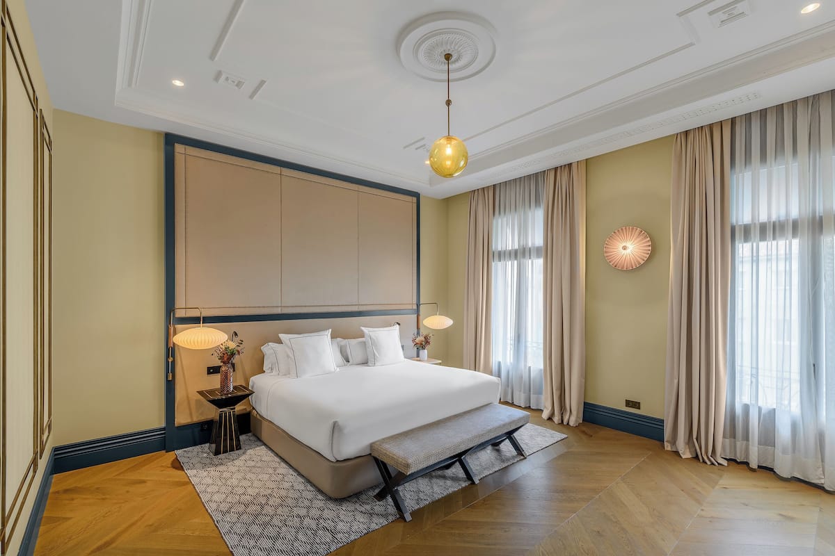 Une chambre spacieuse avec un grand lit, une table de chevet avec des lampes et un banc.