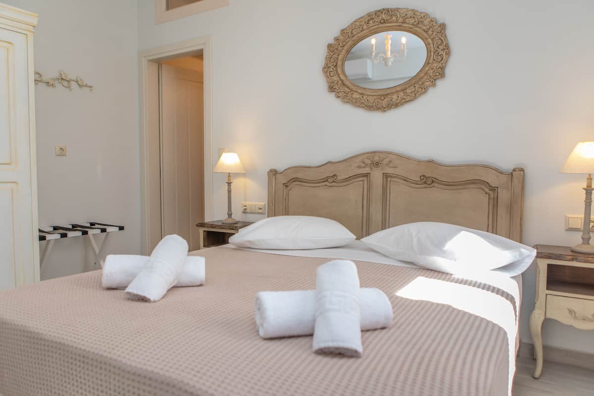 A neatly made bed with rolled towels, a mirror, and bedside lamps in a hotel room.