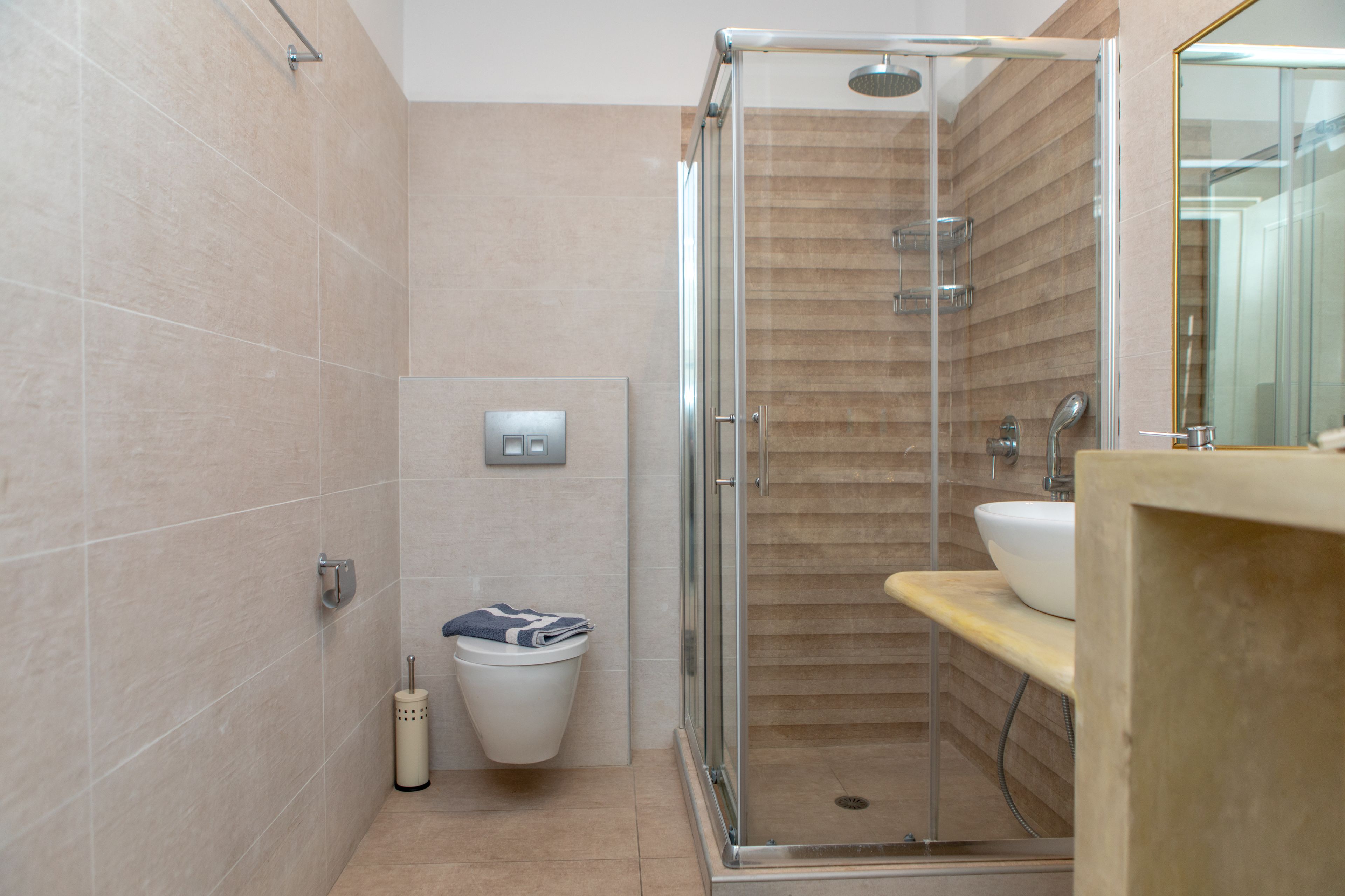 Un baño moderno con cabina de ducha de vidrio, inodoro y lavabo con encimera de madera.