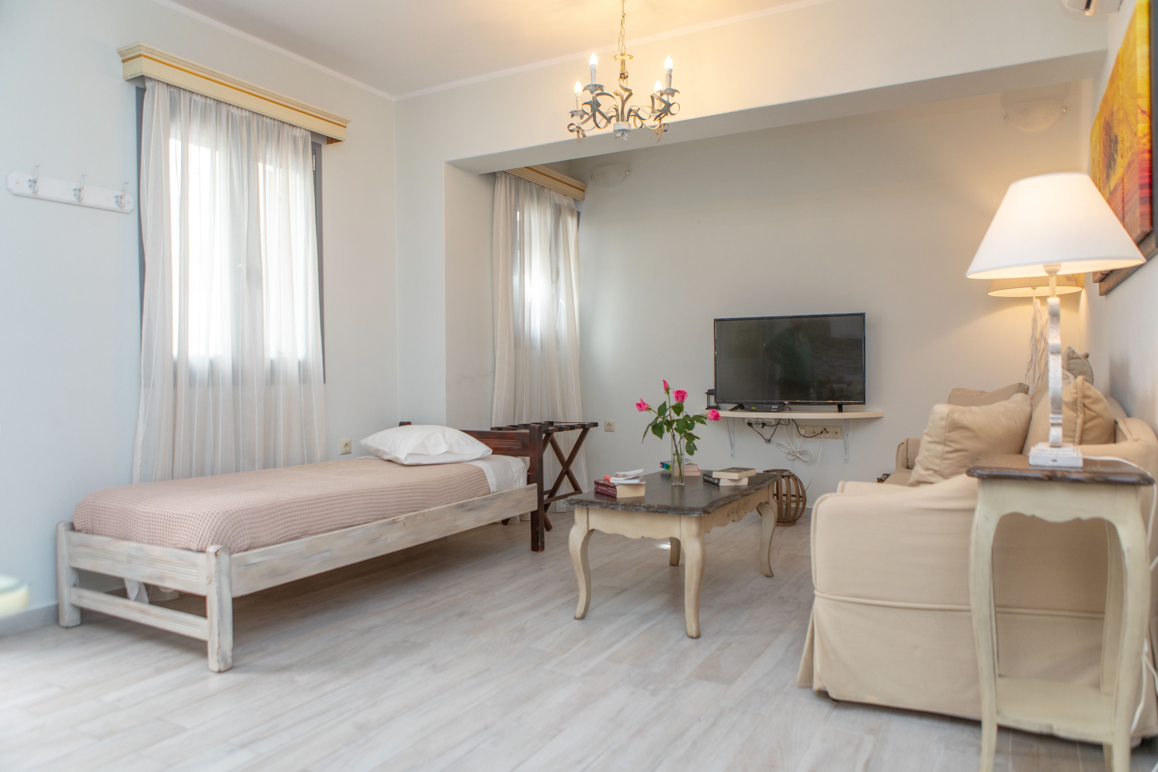 A bedroom with a bed, a bedside table, a lamp, a TV, and a sofa.