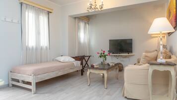 A bedroom with a bed, a bedside table, a lamp, a TV, and a sofa.