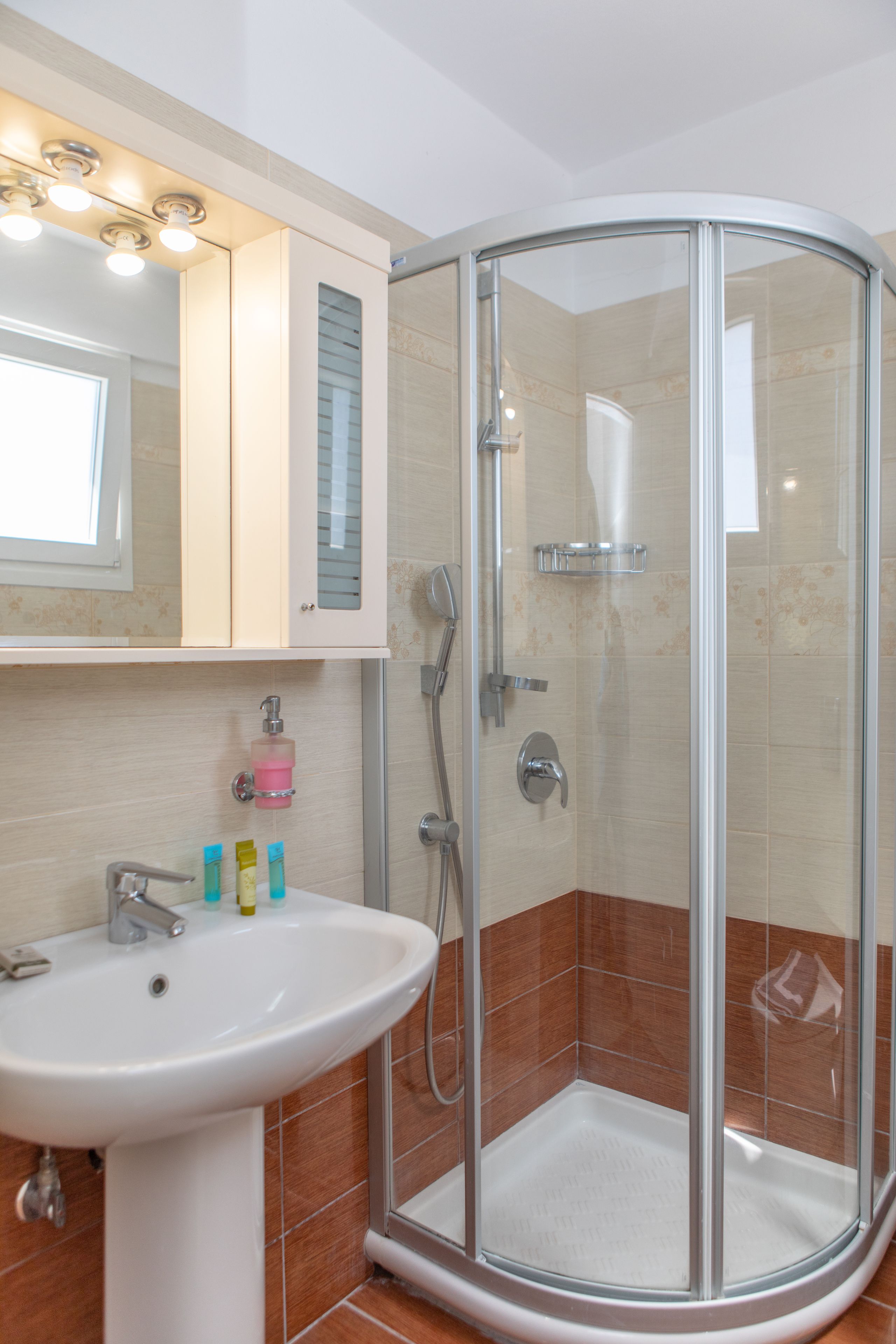 Un bany amb plat de dutxa de vidre, un lavabo i un mirall a sobre.