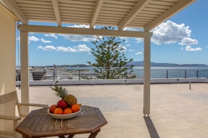 Una mesa con un cuenco de fruta y vistas al mar y a las montañas.