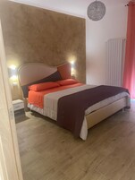 Una camera da letto con un letto, comodini, una lampada a parete e un termosifone.