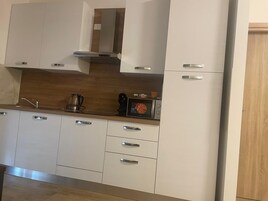 Una cucina moderna con mobili bianchi, una schiena di fiamma in legno e elettrodomestici in acciaio inossidabile.