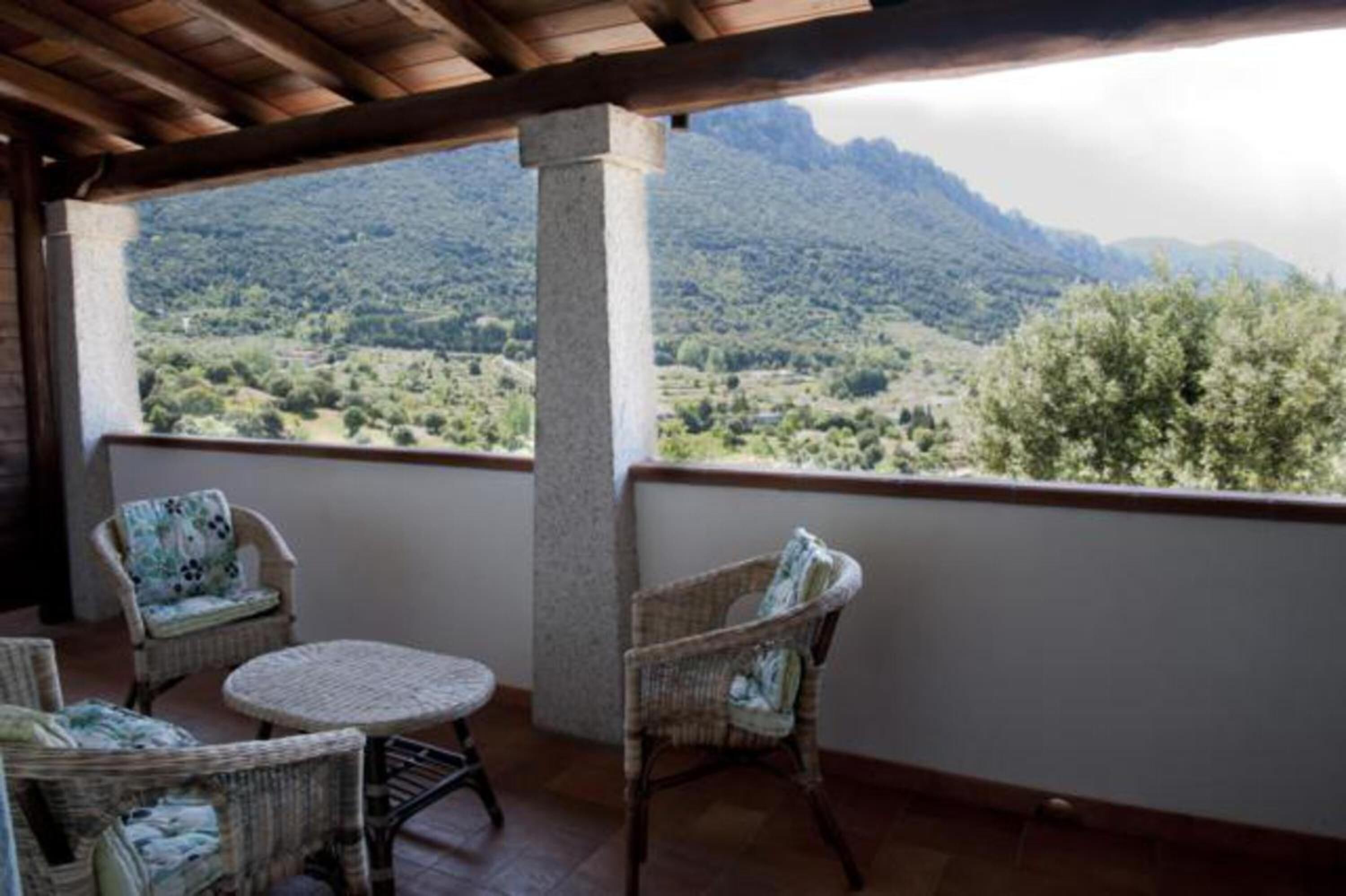 A balcony with wicker furniture and a view of a mountainous landscape.