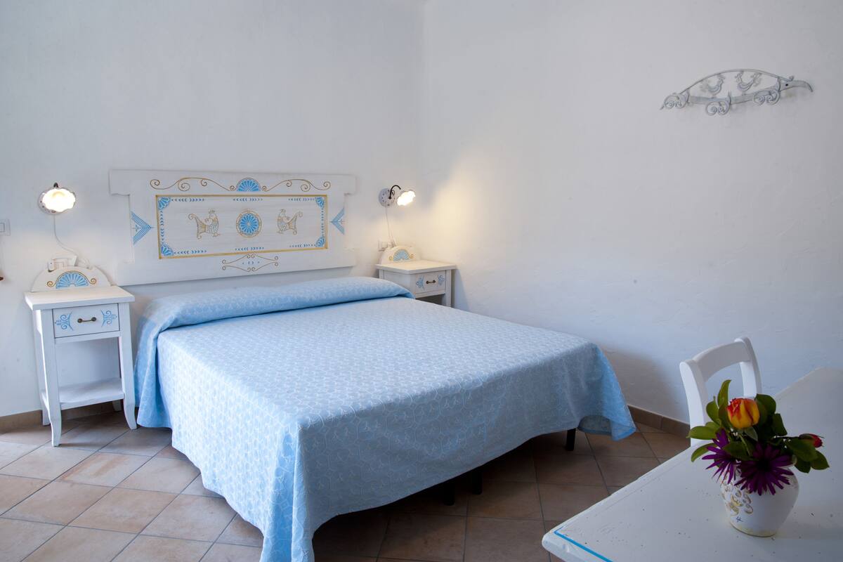 Une chambre à coucher comprenant un lit, deux tables de chevet, une commode, une chaise et un élément décoratif mural.