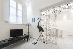 Una habitación con una televisión sobre un mueble, una lámpara y un panel decorativo de metal.