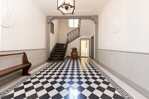 Ein Flur mit Schachbrettfußboden, einer hölzernen Bank, einer Treppe und einem Blumentopf.