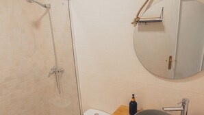 A modern bathroom with a glass-enclosed shower, a toilet, a sink with a mirror above it, and a wooden countertop. - Latas Surf House (Ribamontan al Mar)