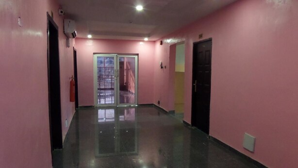 A hallway with pink walls, a glass door, and a black floor. - X Garden Hotel & Suites (Lagos)