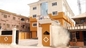 A multi-story building with a central entrance, a gated driveway, and a visible antenna structure. - X Garden Hotel & Suites (Lagos)