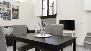 A modern living room with a black dining table, grey sofas, and abstract wall art. - Porta Rossa (Florence)