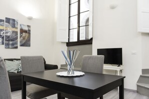 Ein modernes Wohnzimmer mit einem schwarzen Esstisch, grauen Sofas und abstrakter Wandkunst.