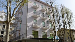 A multi-story building with balconies, a green door, and a visible sign. - Hotel Britta (Rimini)