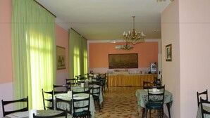 A dining area with tables and chairs, a chandelier, and a painting on the wall. - Hotel Britta (Rimini)