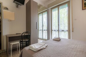 A bedroom with a bed, a desk, a chair, and large windows. - Hotel Britta (Rimini)