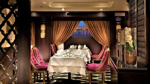 A dining area with a table set for four, two chairs on each side, and a view of a body of water through the window.