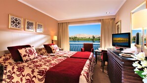 A hotel room with two beds, a desk, a television, and a view of a landscape.