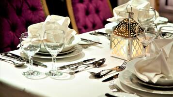 A table set for a formal dining experience with white tablecloths, silverware, and clear glassware.