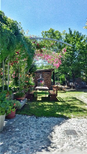 A garden with a stone fireplace, wooden furniture, and potted plants. - Il Germano Reale (Castagnito)
