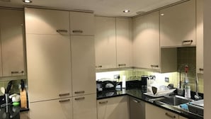 Une cuisine moderne avec des armoires de couleur beige, des comptoirs noirs et un évier en acier inoxydable.