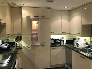 A modern kitchen with white cabinets, a black countertop, and a built-in oven. - Eson2 - The Hayes Place Lodge (London)