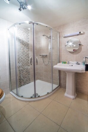 A bathroom with a glass-enclosed shower, a pedestal sink, and a mirror on the wall. - WASTWATER COTTAGE (Holmrook)