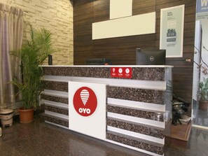 Ein Empfangsschalter mit Logo, einer Uhr und einem Schild mit den Check-in-Zeiten.