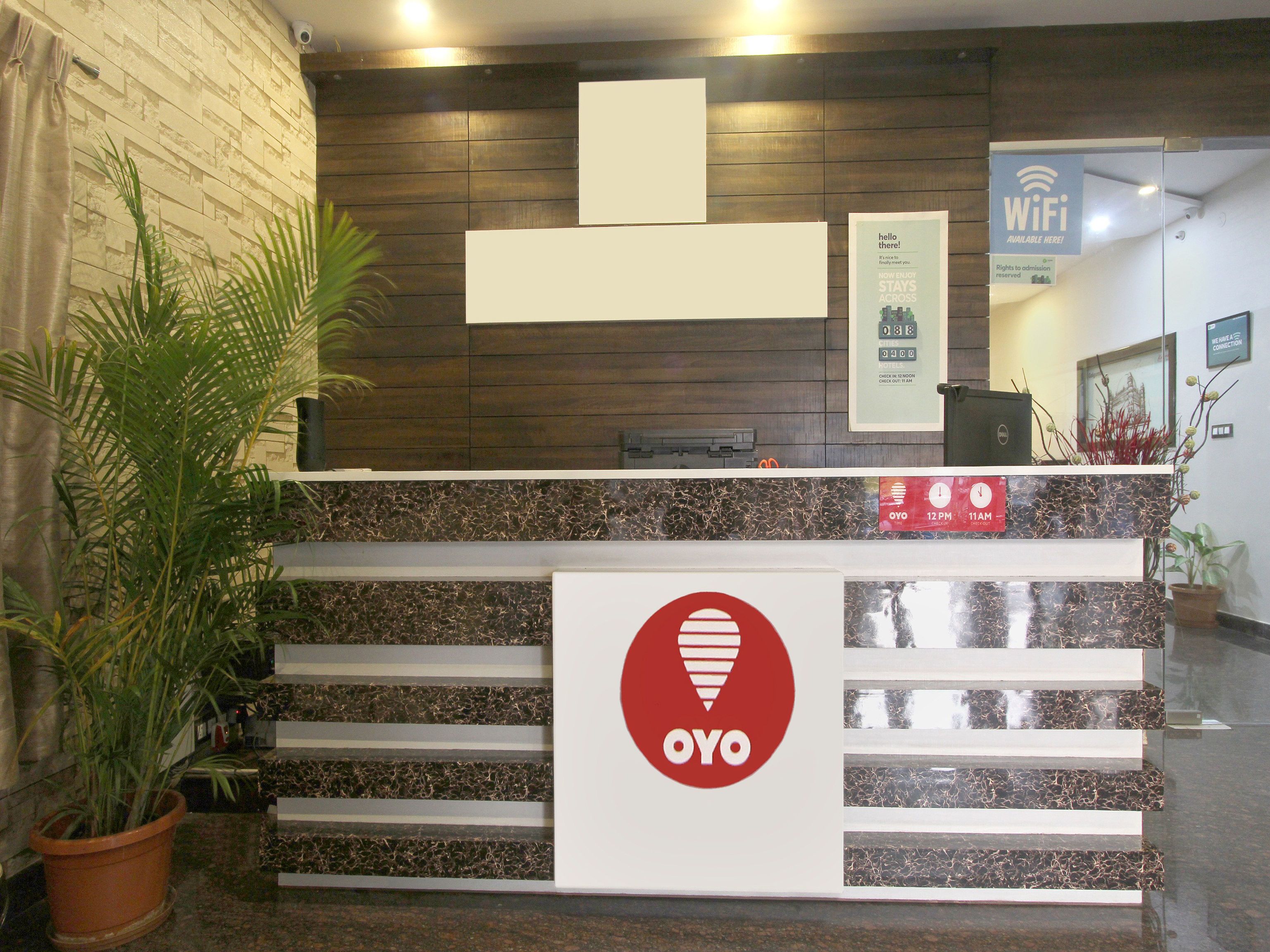 A reception desk with a logo, a WiFi sign, and a clock displaying 12 PM.