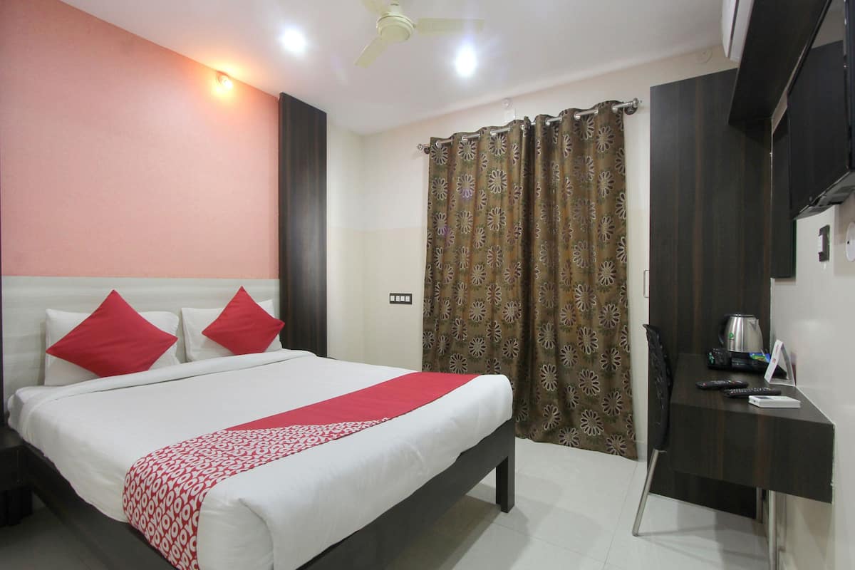 Una habitación de hotel con cama, escritorio, cafetera y cortinas.