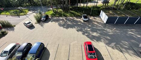 A parking area with several cars, surrounded by trees and greenery.