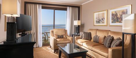 Habitación de hotel con sofá, sillón y televisor de pantalla plana.