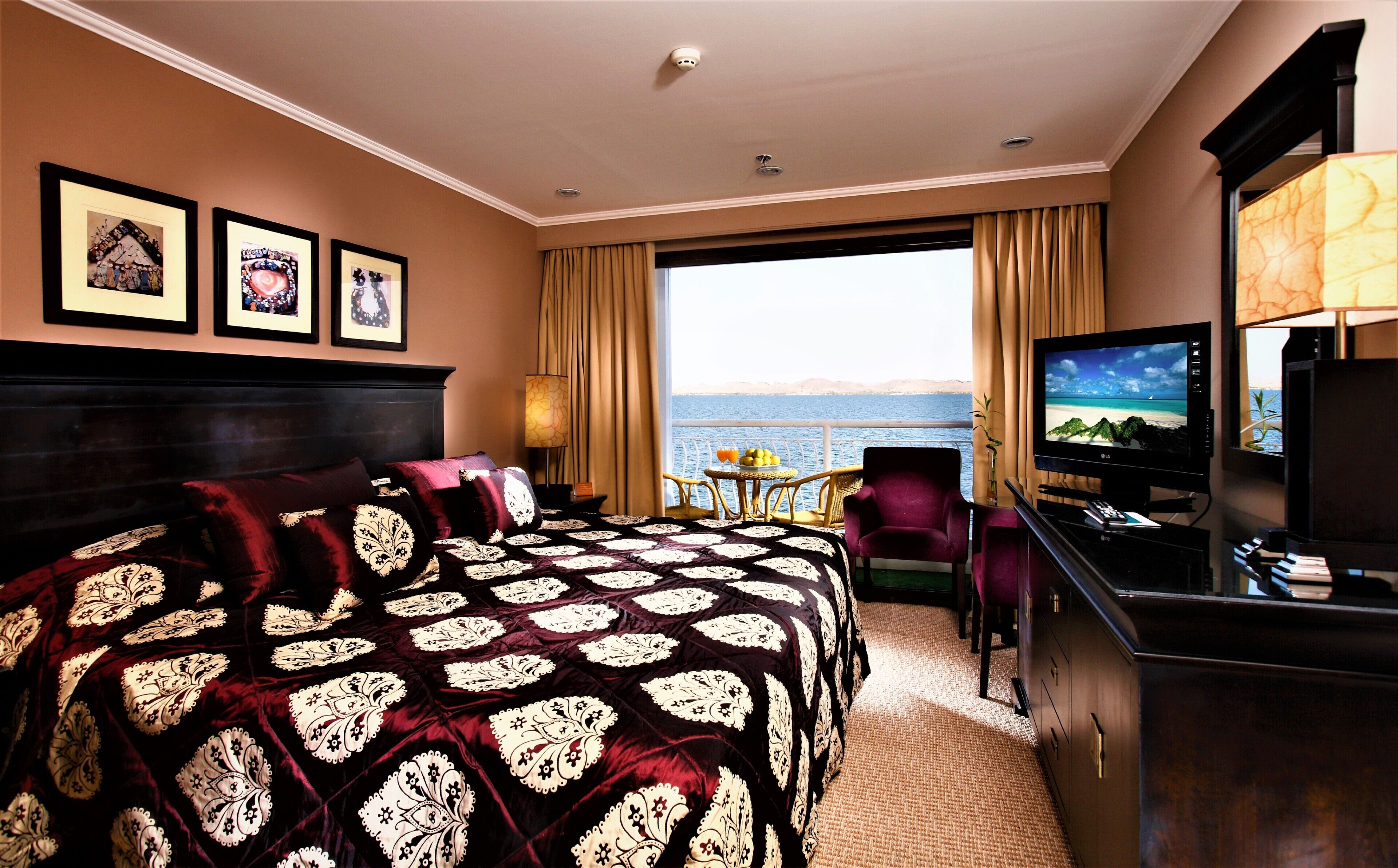 Une chambre d’hôtel avec un grand lit, une télévision, un bureau et une vue sur la mer.
