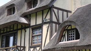 A traditional half-timbered building with exposed wooden beams and thatched roofs. - Les Hauts d'Etretat (Bordeaux-Saint-Clair)