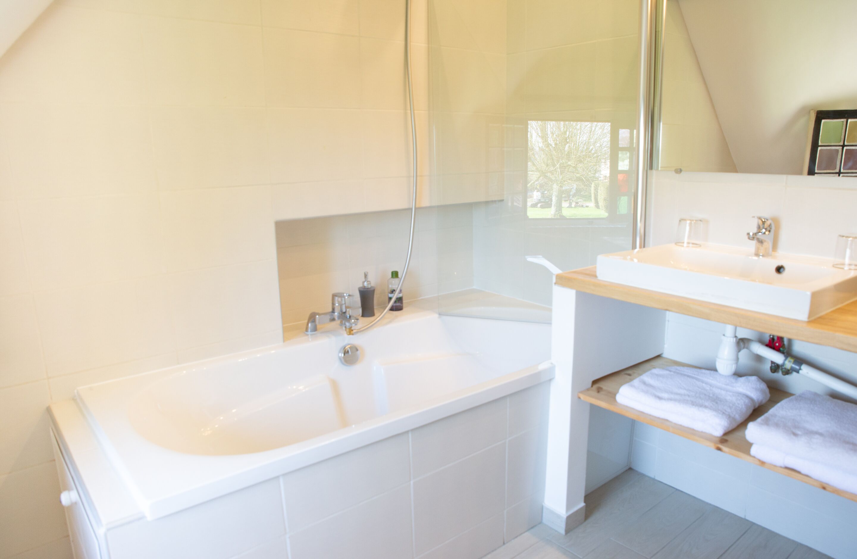 A modern bathroom with a large bathtub, a separate sink area, and a mirror above the sink.