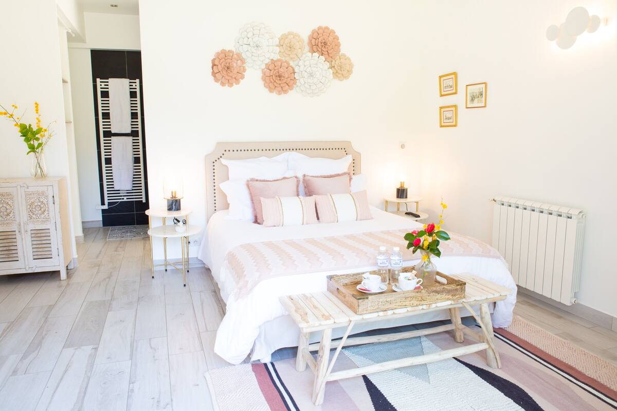 A bedroom with a large bed, bedside tables, a nightstand, a radiator, and a wall with flower decorations.