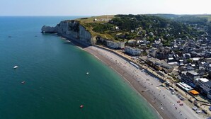 A coastal town with a prominent cliff, a beach, and a mix of residential and commercial buildings. - Les Hauts d'Etretat (Bordeaux-Saint-Clair)