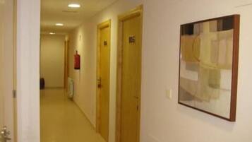 A corridor with doors, a fire extinguisher, and a framed artwork on the wall.