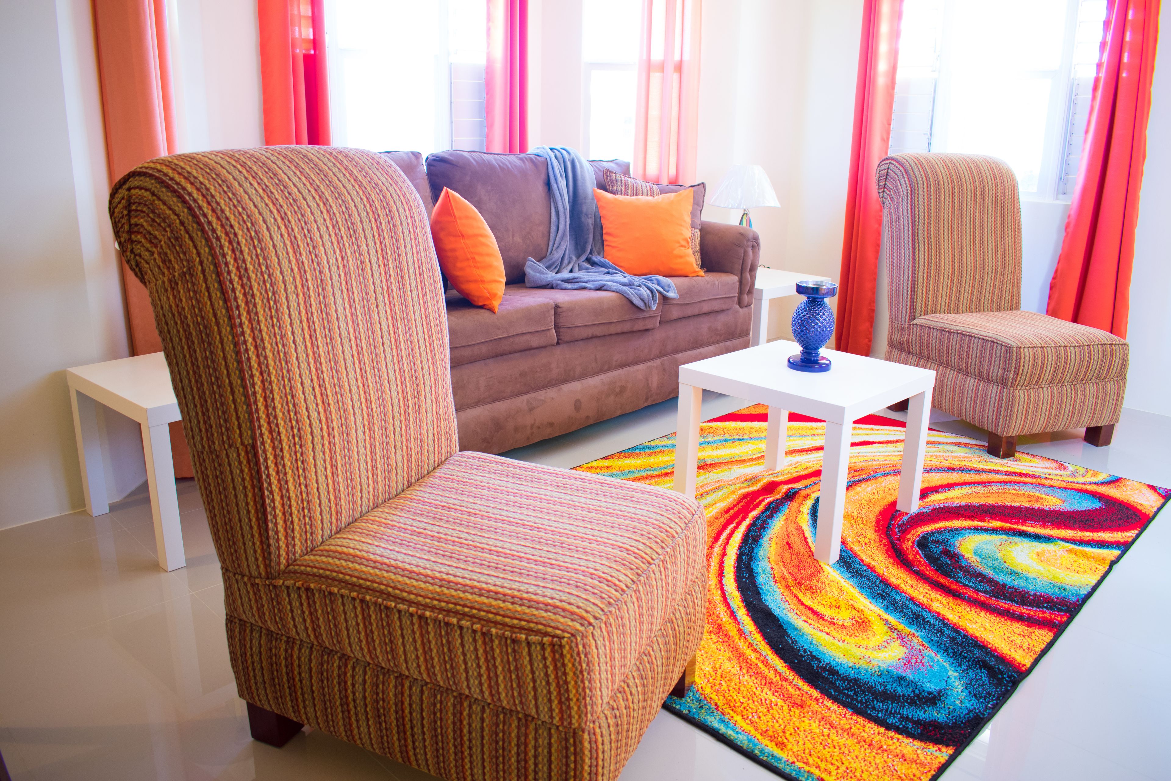 A living room with a sofa, two armchairs, a coffee table, and a colorful rug.