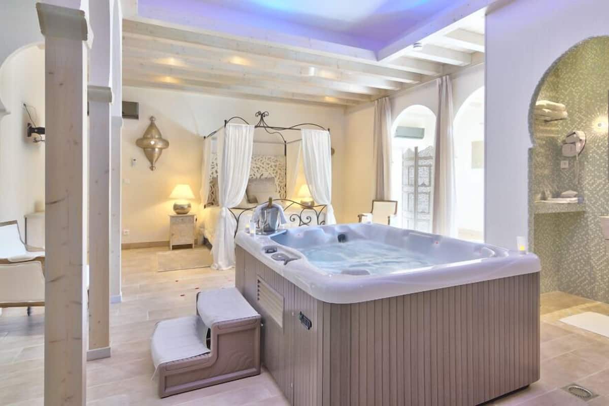 A modern bathroom with a large hot tub, a separate shower area, and a vanity with a mirror.