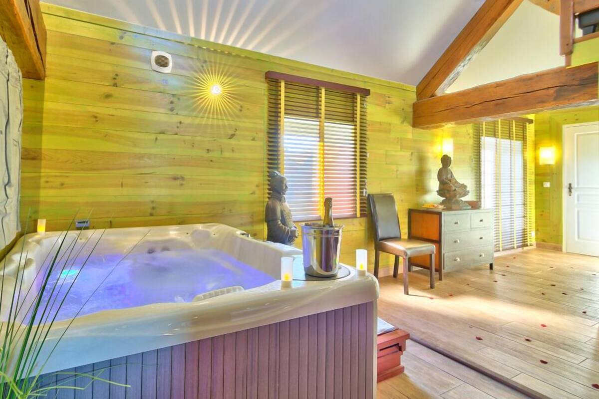 A room with a wooden interior, a hot tub, a statue, and a chair.